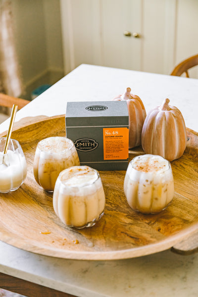 Pumpkin shaped glasses with Autumn Leaves iced latte on a wooden tray with box of Autumn Leaves tea.