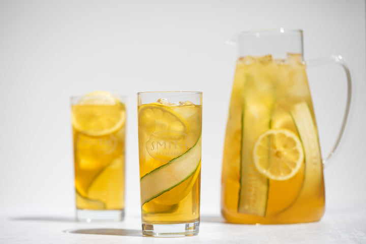 Two glasses and pitcher of Cucumber Mint Iced Tea with cucumber garnish.