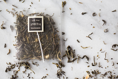 Loose full leaf tea and sachet of White Petal on marble background.