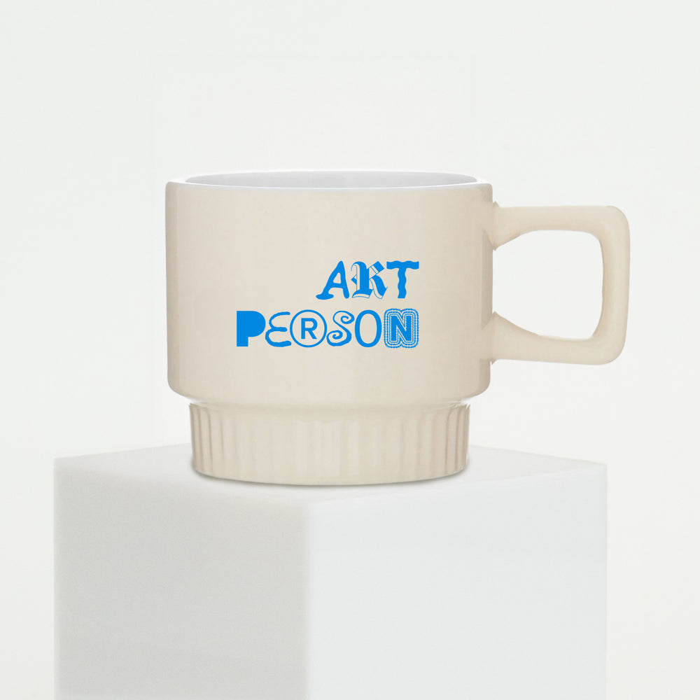 Beige mug with blue text 'ART PERSON' on a white background