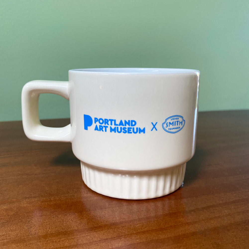 White mug with 'Portland Art Museum' and 'Smith Tea' logos on a wooden surface.