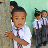 School boy standing beside a tree in Darjeeling, India.