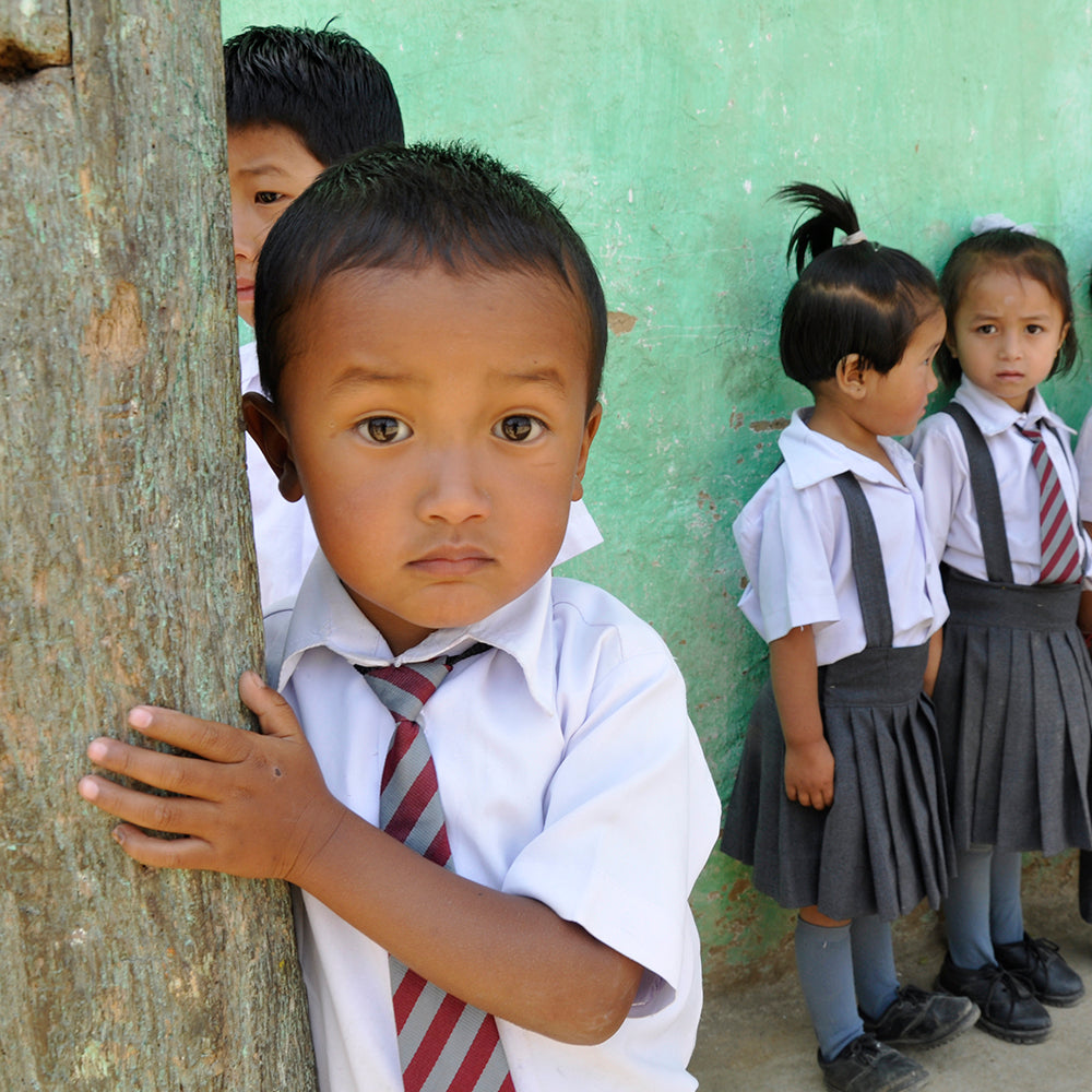 School boy standing beside a tree in Darjeeling, India.