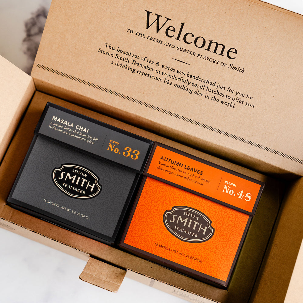 Two tea packages from Smith Tea, one black and one orange, inside a cardboard box with branding text.