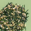 Pile of loose leaf Garden Party green tea to show gyokuro green tea, lavender, hyssop and chamomile against a green background.