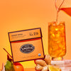 Ginger Rising tea being poured into a glass with a packaging and ingredients on an orange background