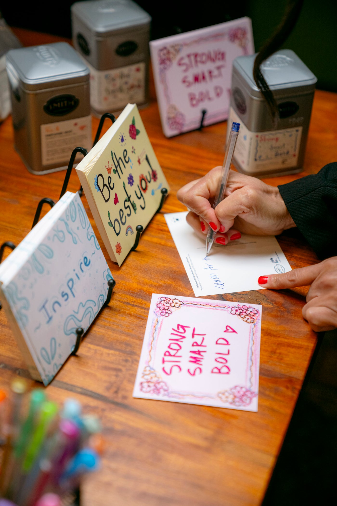 Hand writing on a Girls Inc. post card that says "Strong, Smart, Bold".