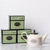 Three cartons of green tea with a white porcelain teapot.