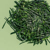 Loose leaf gyokuro green tea to show bright green, flat tea leaves against a green background.