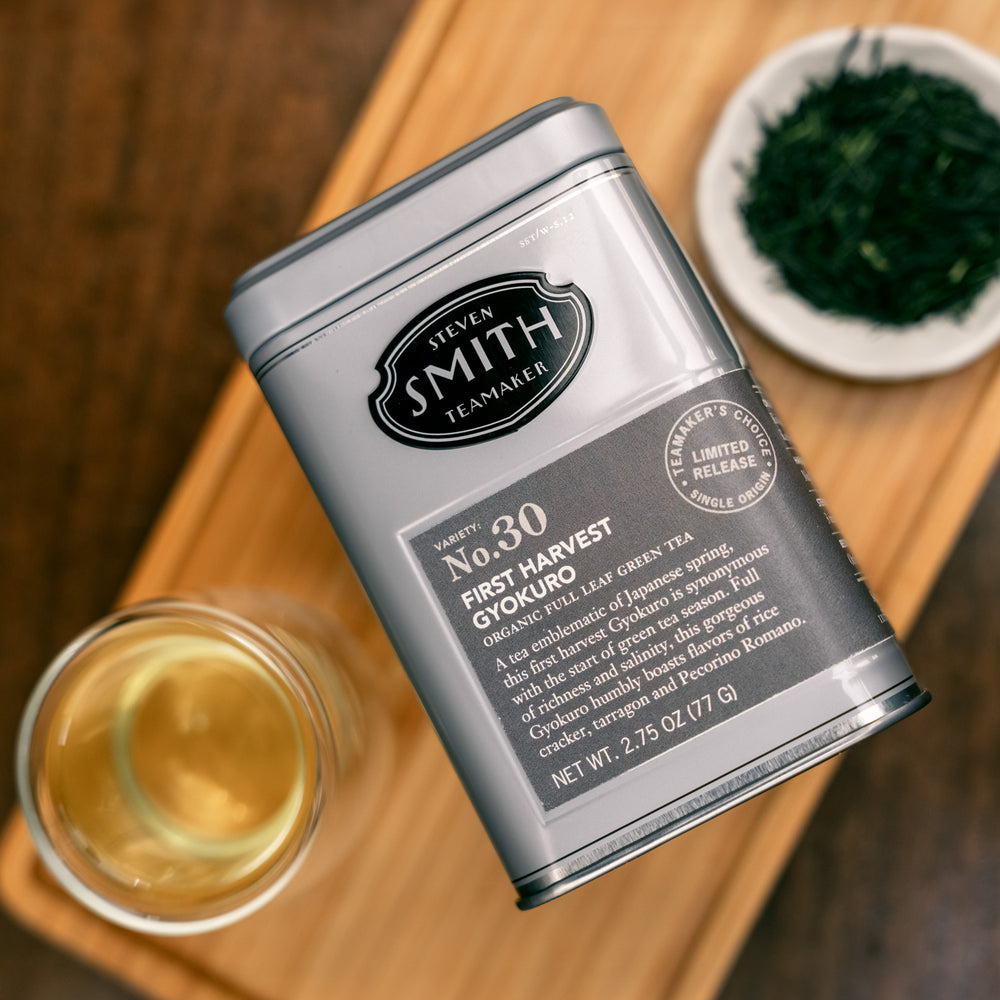 Grey tin of First Harvest Gyokuro with a dark grey label and black Smith Teamaker logo with a cup of tea and bowl of tea leaves in the background.