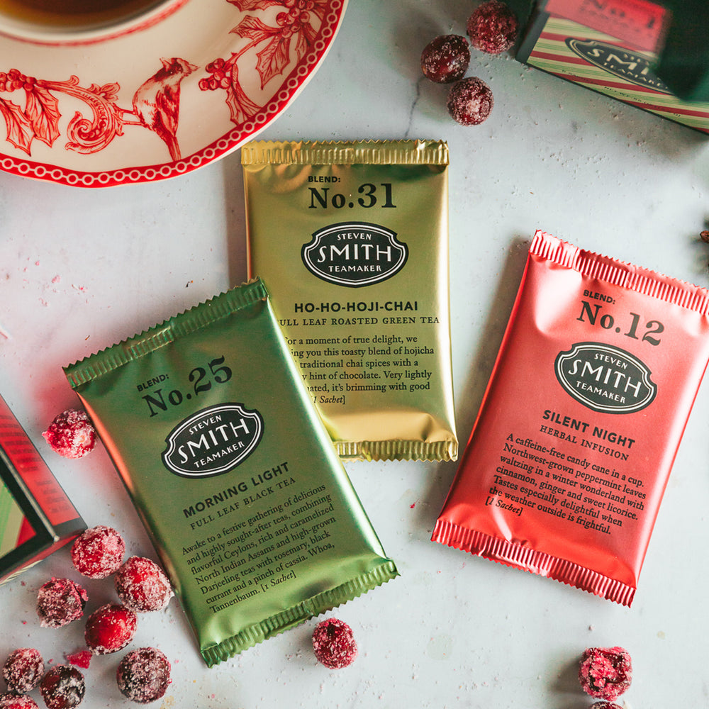 One green sachet of Morning Light, one gold sachet of Ho-Ho-Hoji-Chai and one red sachet of Silent Night on a festive holiday table.