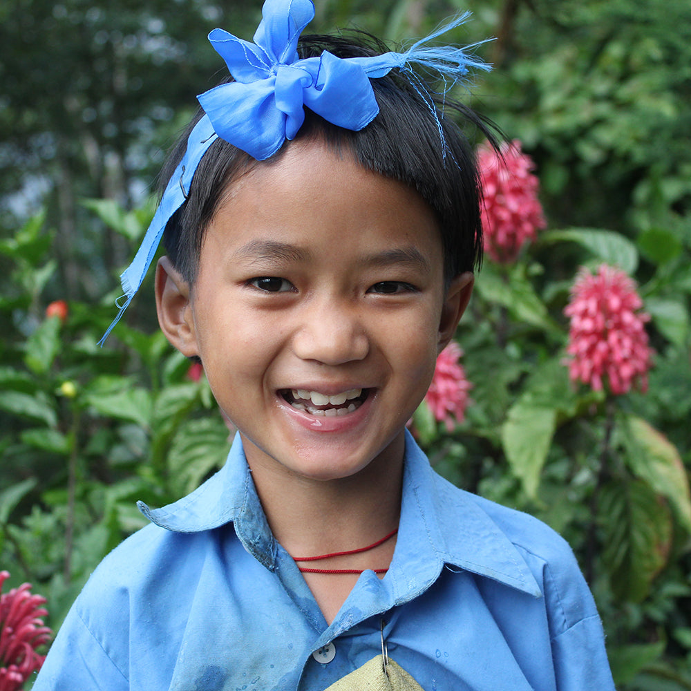 Schoolgirl with a big smile wearing her bright blue school uniform.