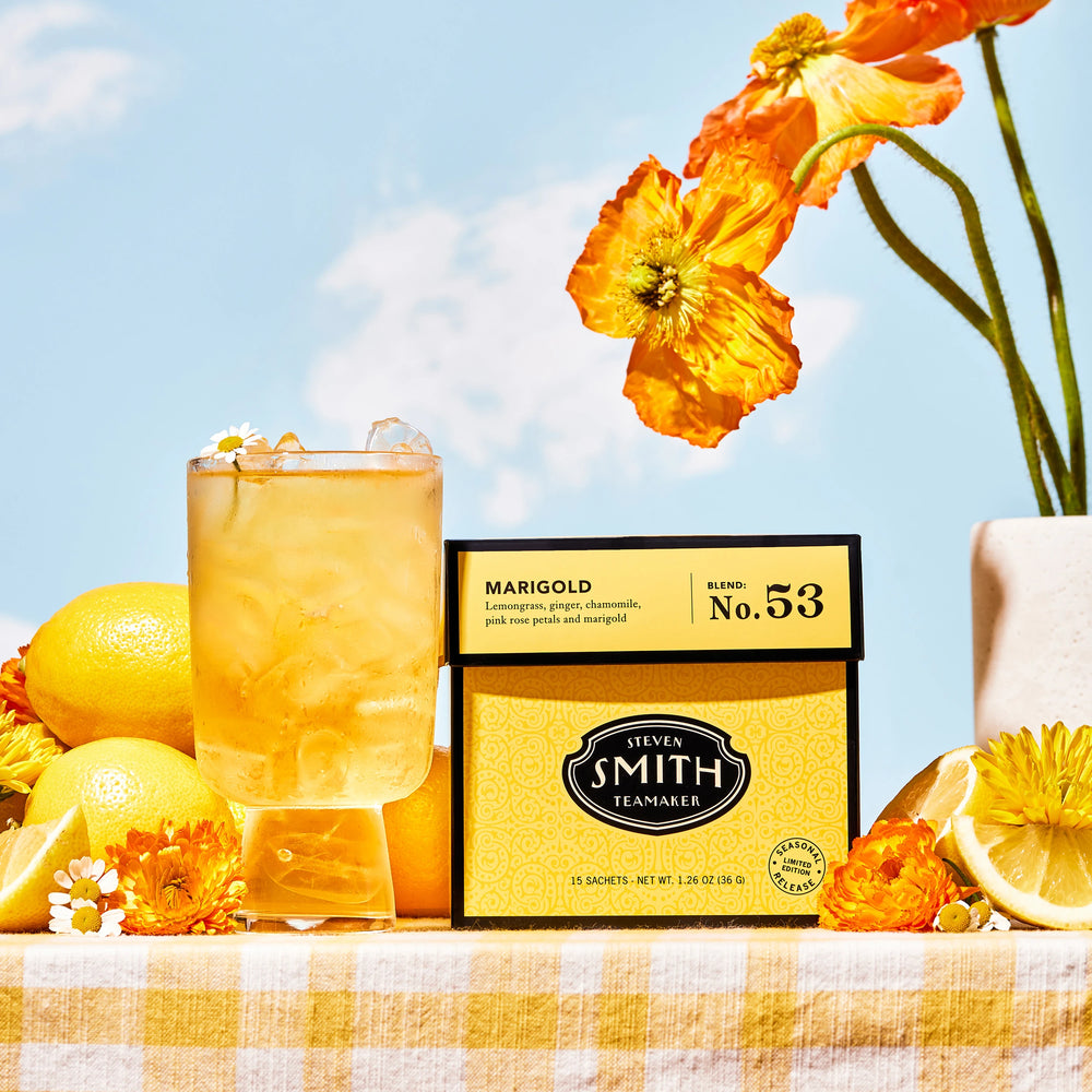 Marigold in an iced glass with ingredients on a yellow and white gingham table cloth and blue skies in background. 