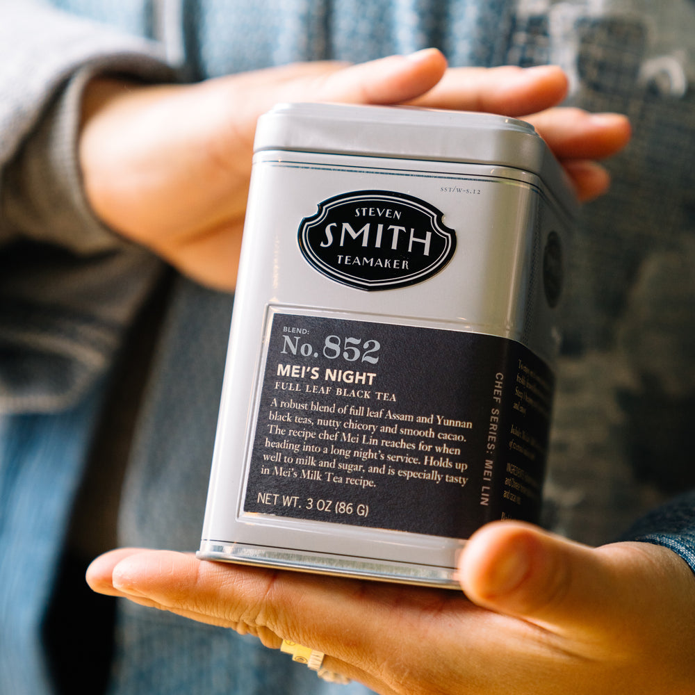 Chef Mei Lin holding silver tin of Mei's Night with black label.