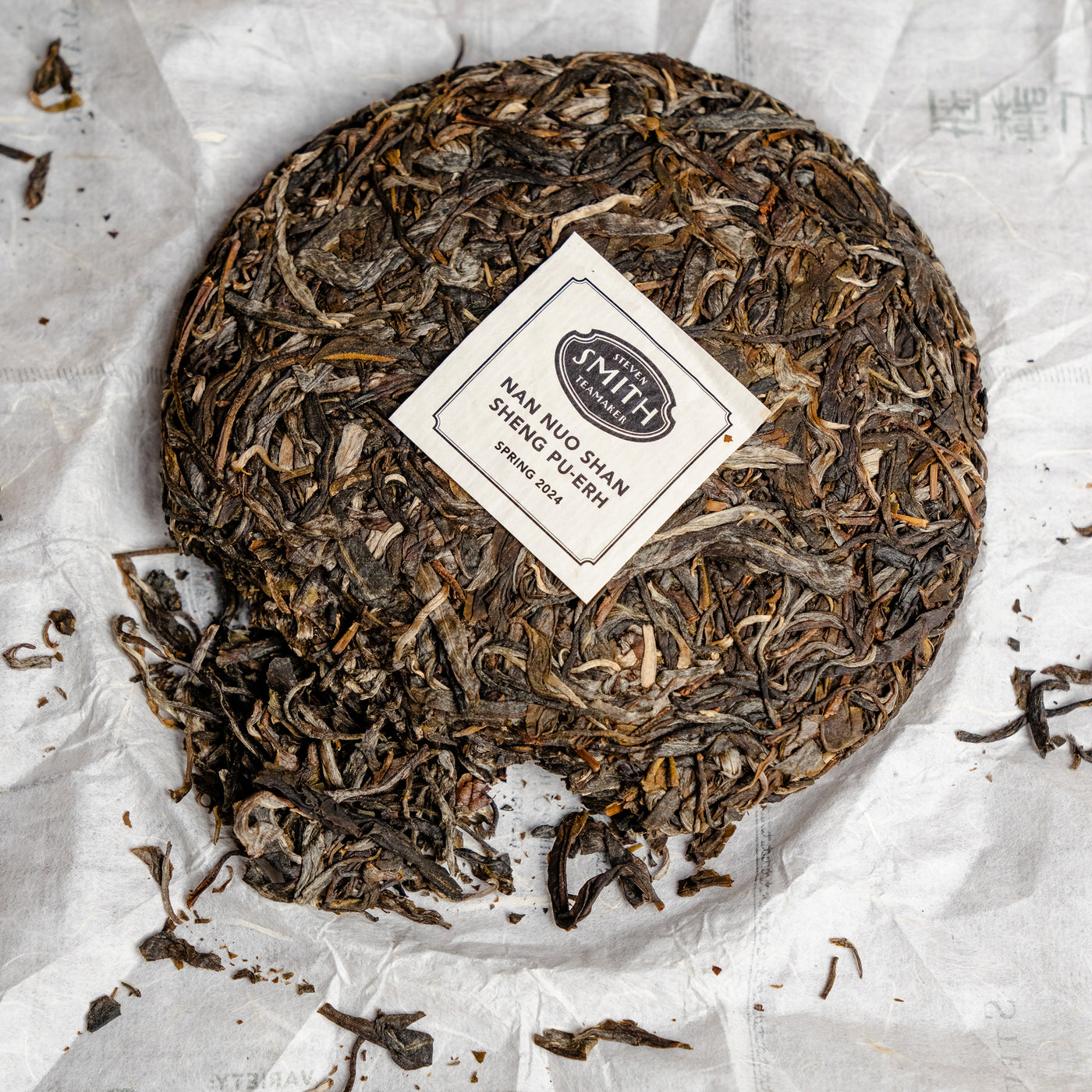 Close up view of Nan Nuo Shan Sheng Pu-erh cake with label in the center of the cake.