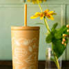 Yellow tumbler with straw and Smith logo next to a plant