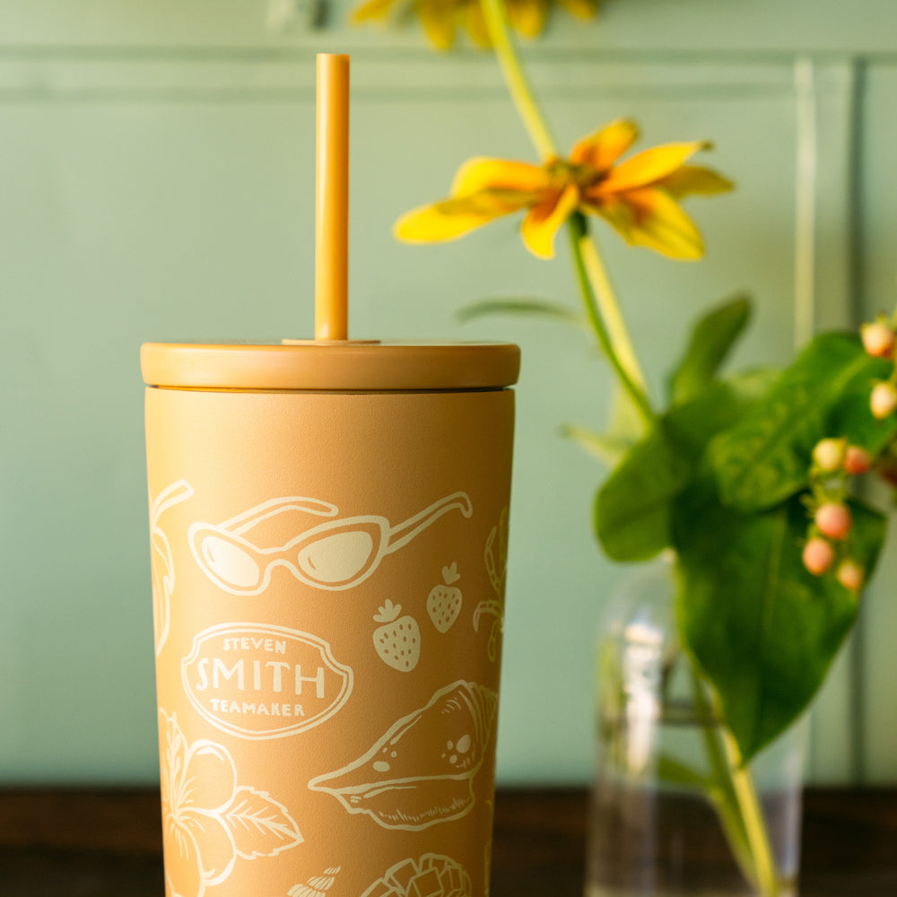 Yellow tumbler with straw and Smith logo next to a plant