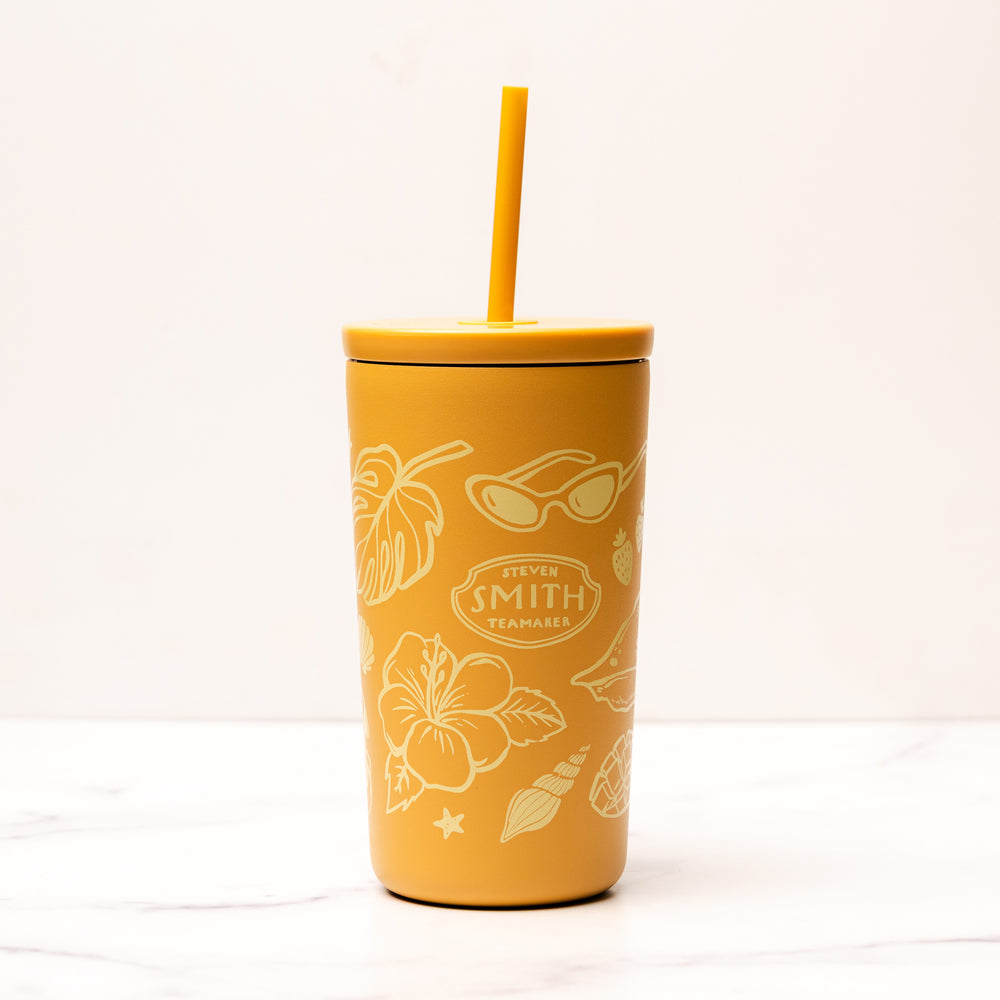 Yellow tumbler with floral and leaf patterns on a white background