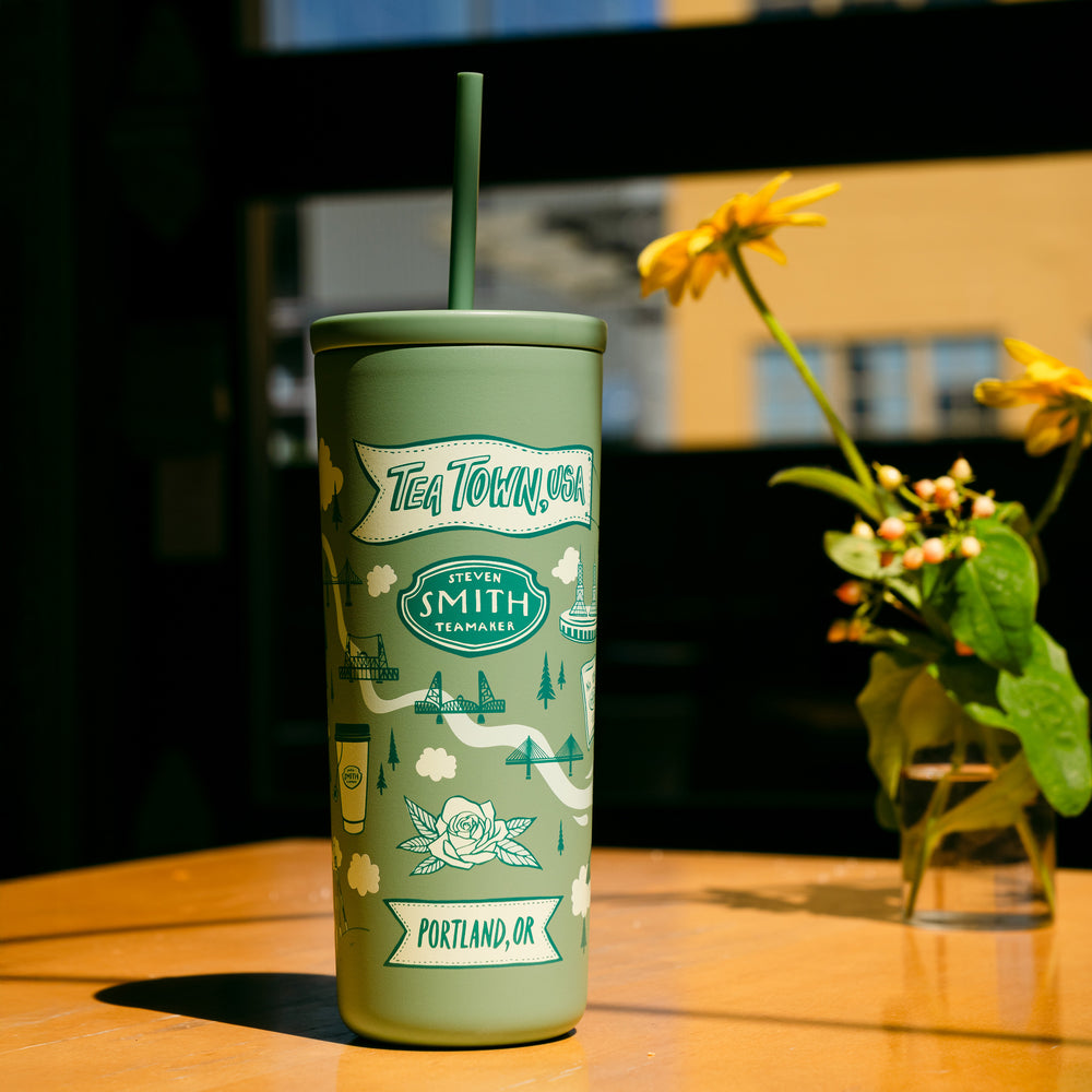 Green tumbler with branding on a wooden table with a blurred background