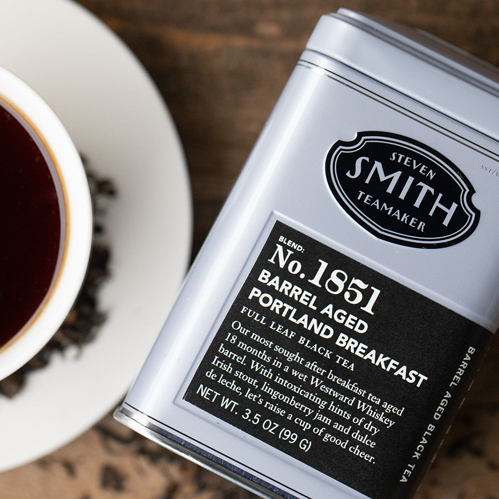 Silver tin of barrel aged portland breakfast tea with black label on wooden table.