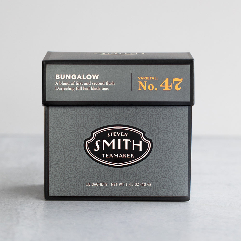 Black carton of tea  on a grey table with a white background.