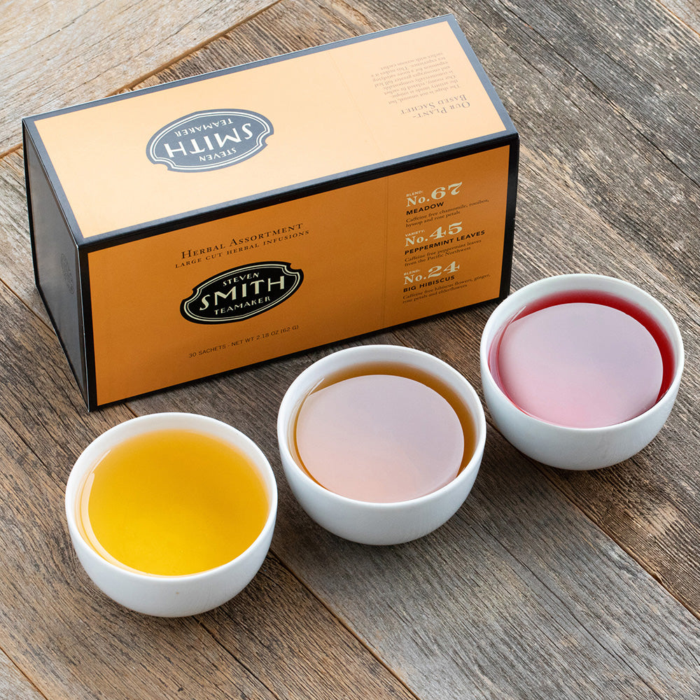 Orange box with black trim on a wooden table with three porcelain cups filled with tea.