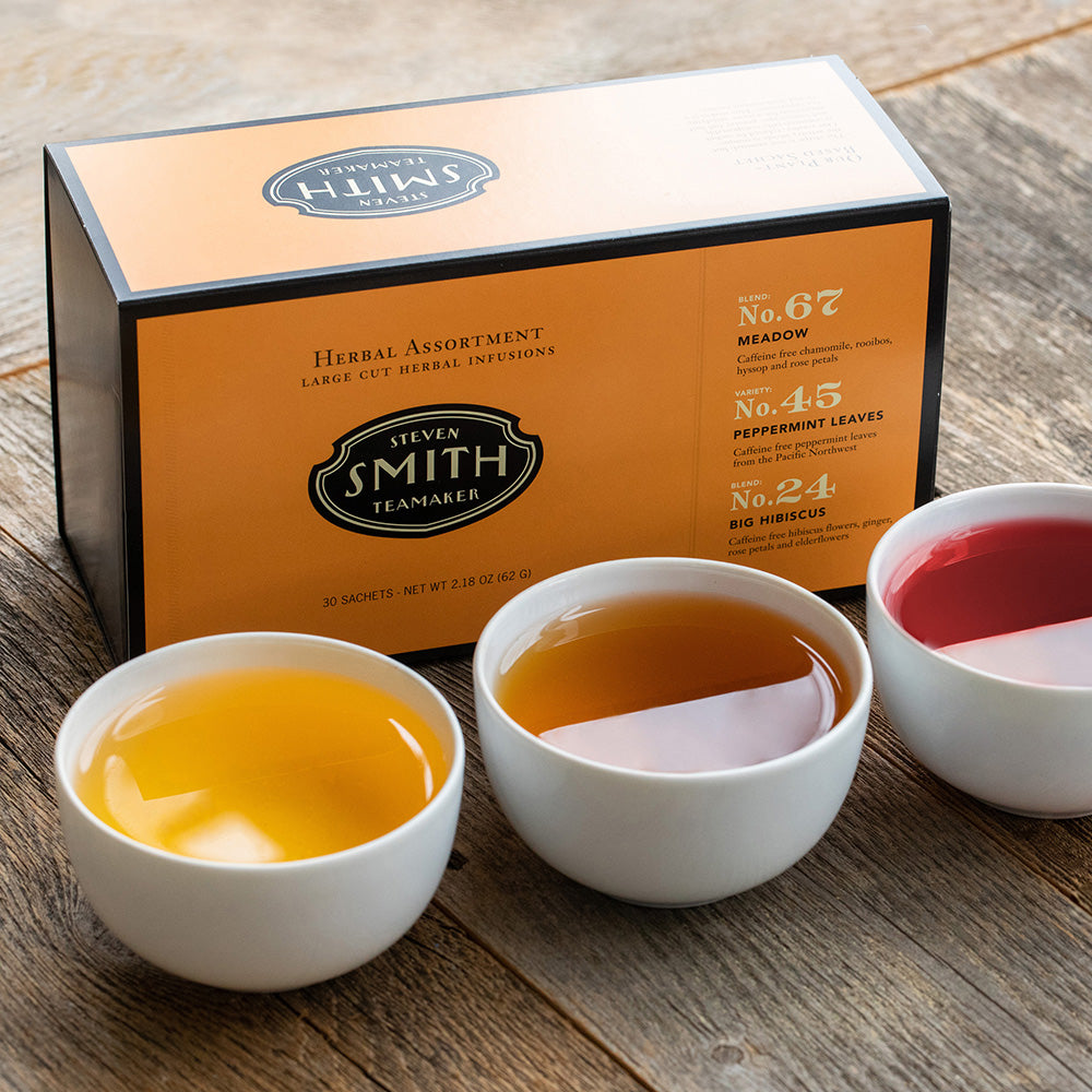 Orange box with black trim on a wooden table with three porcelain cups filled with tea.