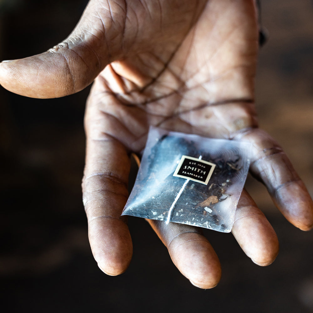 Hand holding sachet of tea.